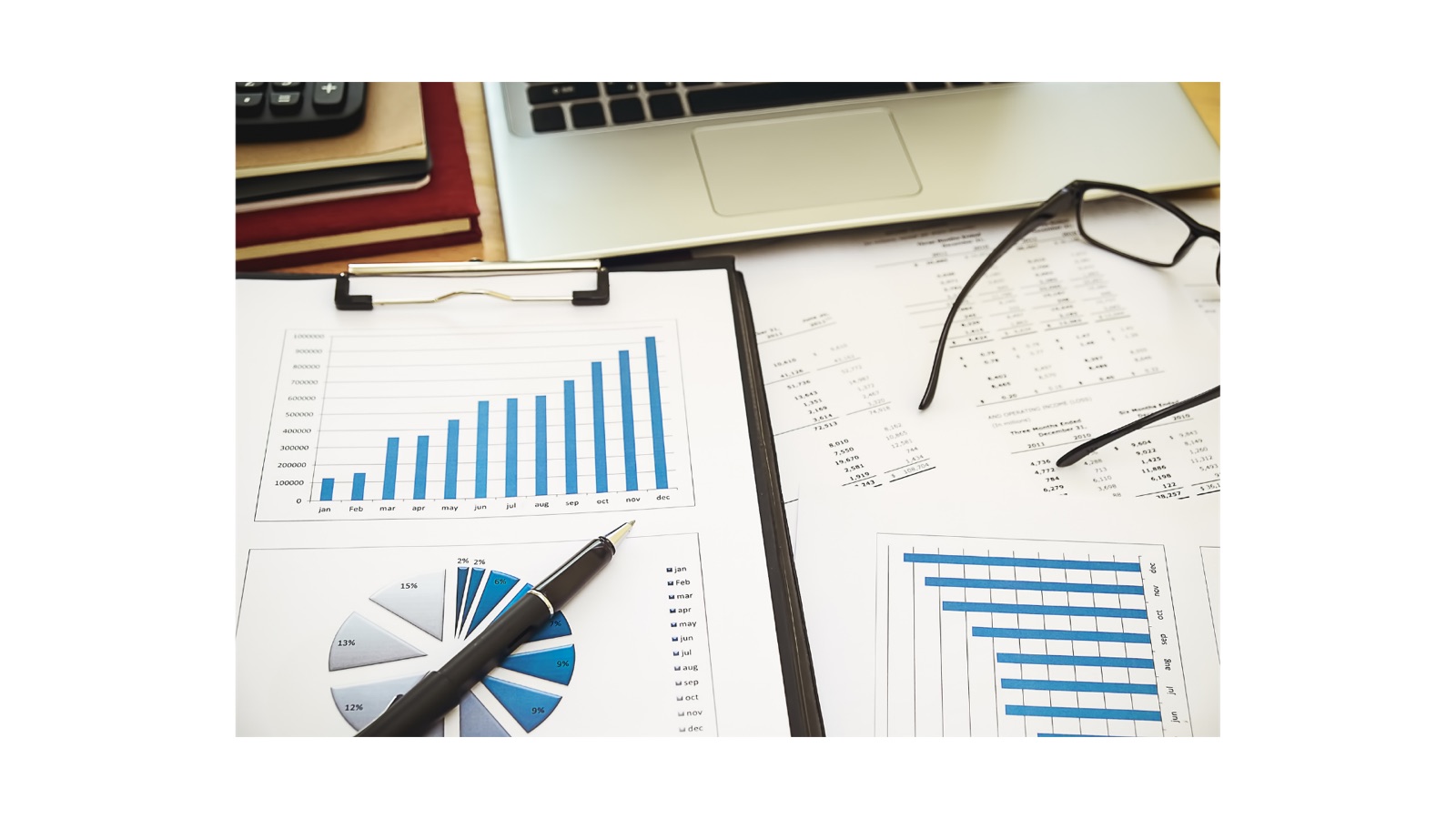Printed charts and reports on a desk beside a laptop